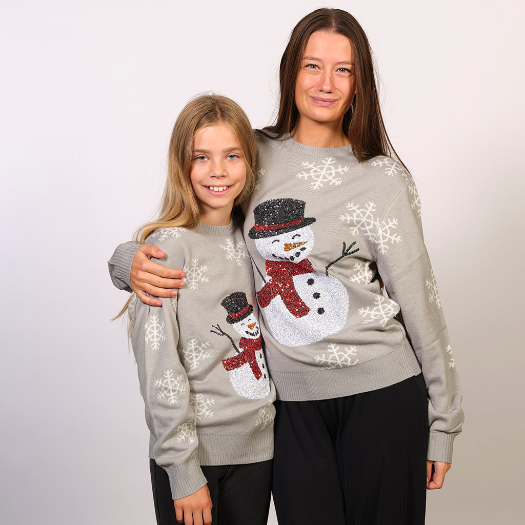 Una donna e un bambino che indossano un maglione natalizio grigio con un pupazzo di neve.